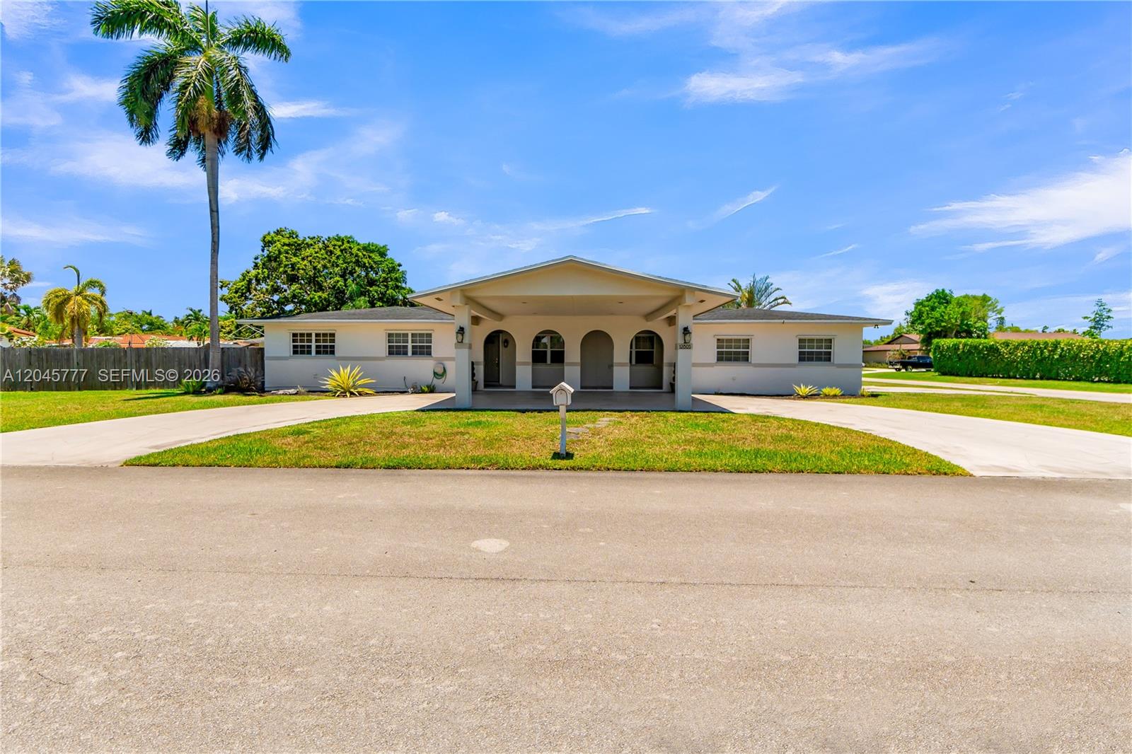 A single-story house with a covered entryway and a circular driveway under a blue sky — 12805 SW 193rd Ter, Miami FL 33177, MIAMI, FL