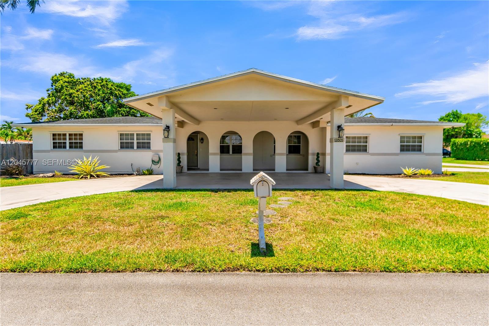 A single-story house features a large covered entryway with arched openings and a concrete driveway — 12805 SW 193rd Ter, Miami FL 33177, MIAMI, FL