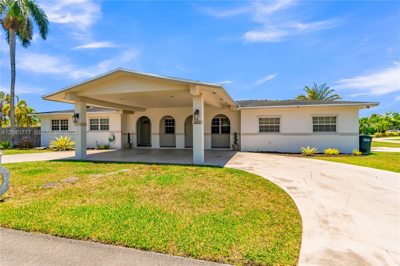 A single-story house features a large covered carport, arched entryways, and a concrete driveway — 12805 SW 193rd Ter, Miami FL 33177, MIAMI, FL