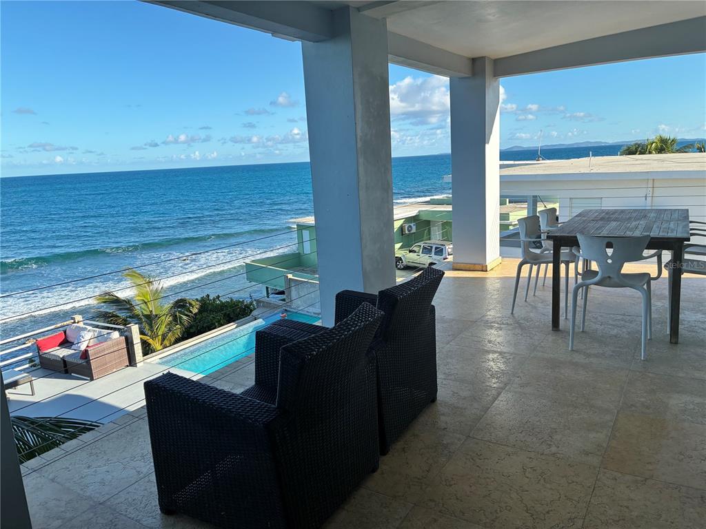 A covered balcony features tile flooring, outdoor seating, and a view of the ocean — 365 NORTH SHORE POINTE, VIEQUES, PR