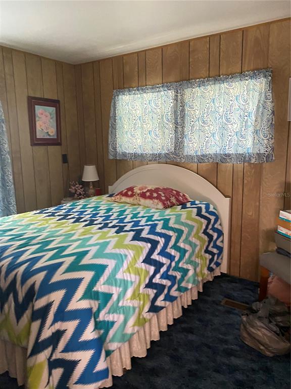 A bedroom features wood-paneled walls, a chevron-patterned bedspread, and blue carpet — 1318 CR 461, LAKE PANASOFFKEE, FL