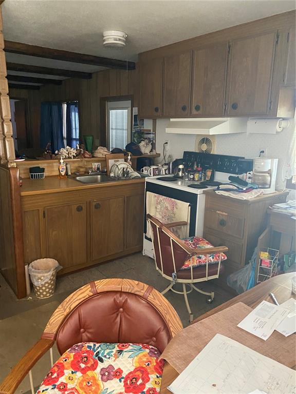 A kitchen features wood cabinets, a white stove, and a sink with a floral chair — 1318 CR 461, LAKE PANASOFFKEE, FL