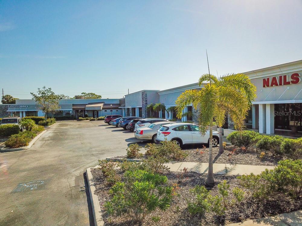 An exterior view of a commercial strip mall with a parking lot and palm tree — 7421 MANATEE AVENUE W UNIT 7453, BRADENTON, FL