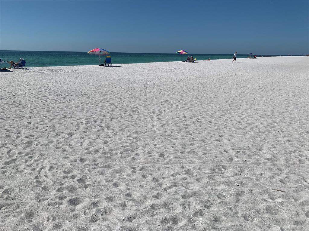 A wide, white sand beach with several colorful umbrellas and people near the ocean — 3806 GULF OF MEXICO DRIVE UNIT C310, LONGBOAT KEY, FL