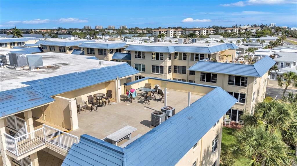 An elevated view of a building rooftop terrace featuring patio furniture and blue roofing — 3806 GULF OF MEXICO DRIVE UNIT C310, LONGBOAT KEY, FL