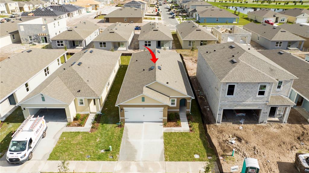 An aerial view shows a tan single-family house with a red arrow pointing to its roof — 2847 COMMON CRANE COURT, HARMONY, FL