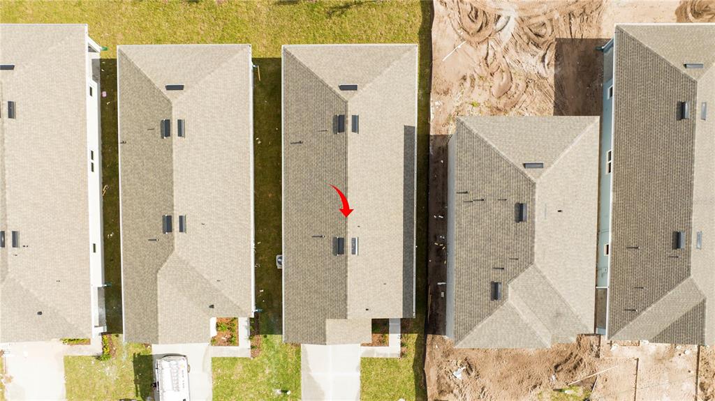 An aerial view shows the shingled roofs of several suburban houses with a red arrow — 2847 COMMON CRANE COURT, HARMONY, FL