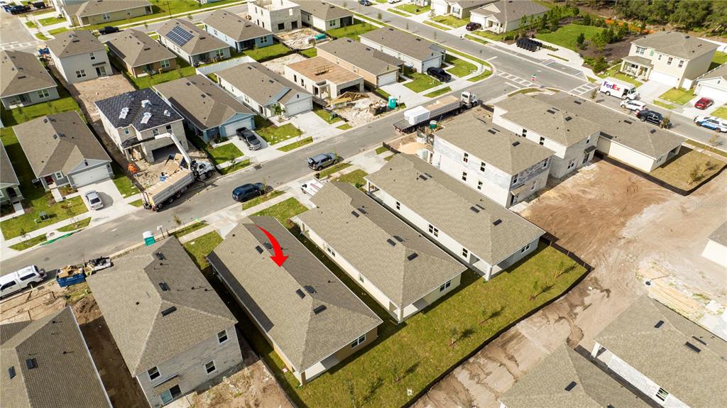 An aerial view shows a suburban neighborhood with several houses and a red arrow pointing to a roof — 2847 COMMON CRANE COURT, HARMONY, FL