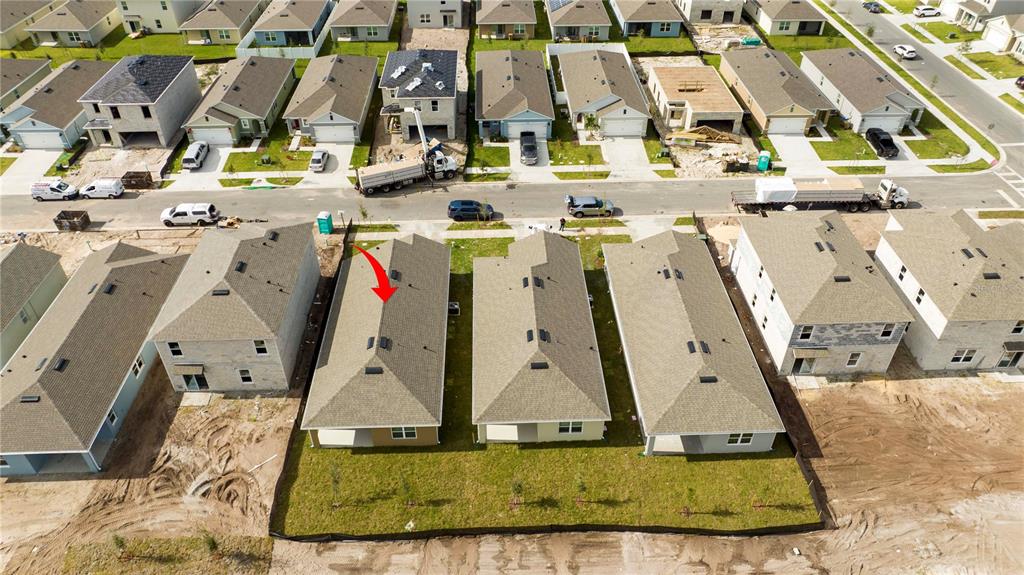 An aerial view shows a row of newly constructed suburban houses with a red arrow — 2847 COMMON CRANE COURT, HARMONY, FL