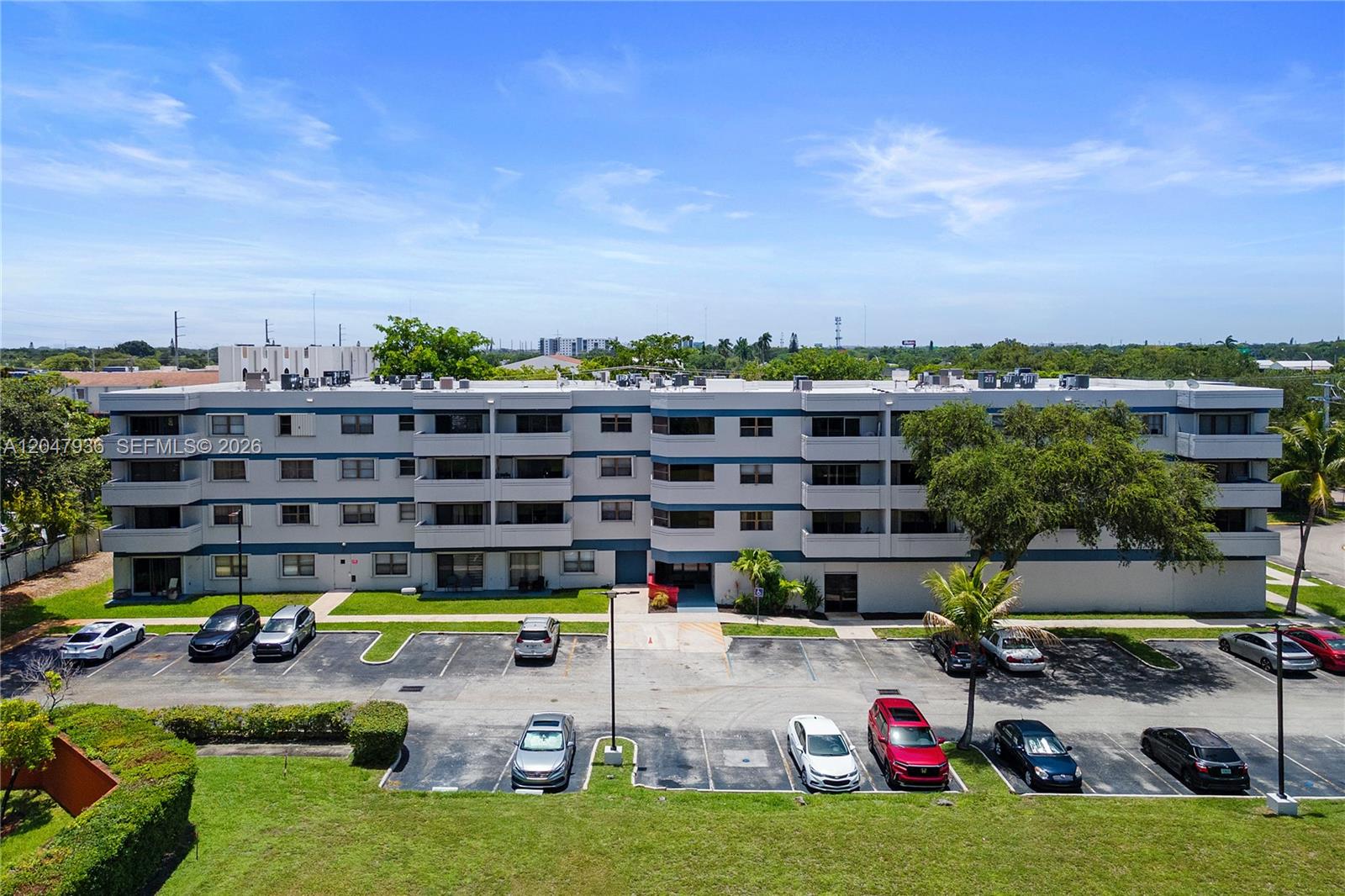 An aerial view shows a multi-story apartment building with a parking lot in front — 1891 N 61st Ave # B215, Hollywood FL 33024, HOLLYWOOD, FL