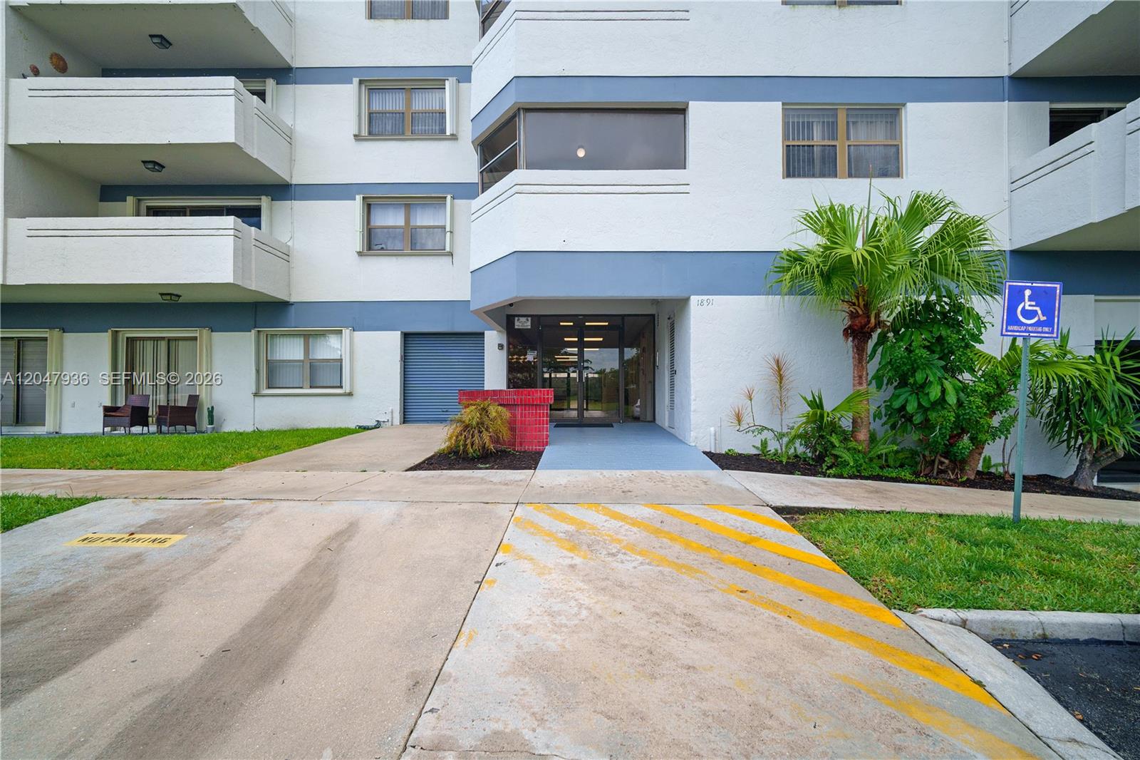 The exterior of a multi-story apartment building features a ground-level entrance and a handicap sign — 1891 N 61st Ave # B215, Hollywood FL 33024, HOLLYWOOD, FL