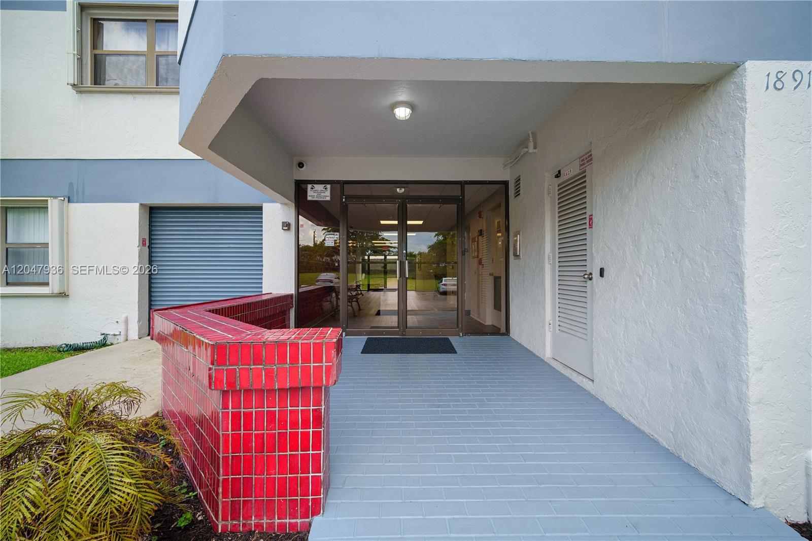 The exterior entrance features a red tiled planter, gray brick flooring, and glass double doors — 1891 N 61st Ave # B215, Hollywood FL 33024, HOLLYWOOD, FL