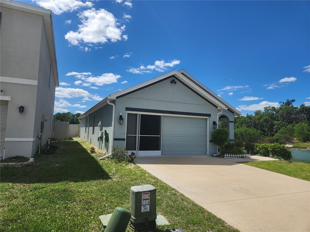 A light blue single-story house with a garage and a screen door entrance — 6643 LONGBOAT DRIVE, BROOKSVILLE, FL