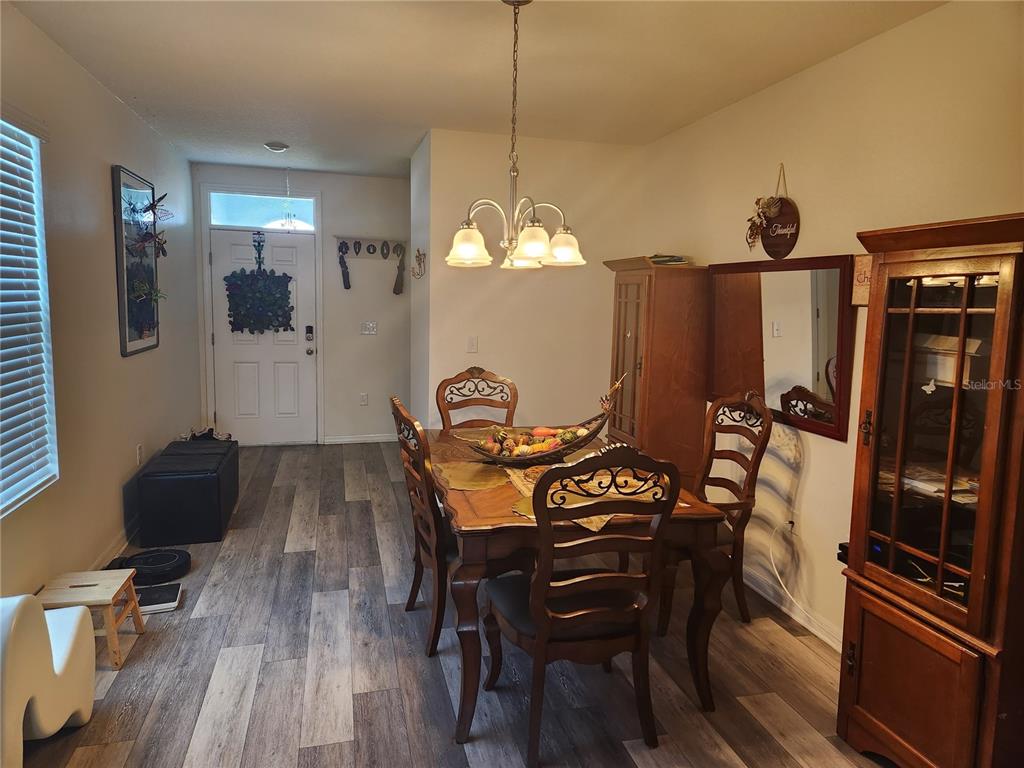 A dining room features wood-look flooring, a wooden table with chairs, and a hanging light fixture — 6643 LONGBOAT DRIVE, BROOKSVILLE, FL