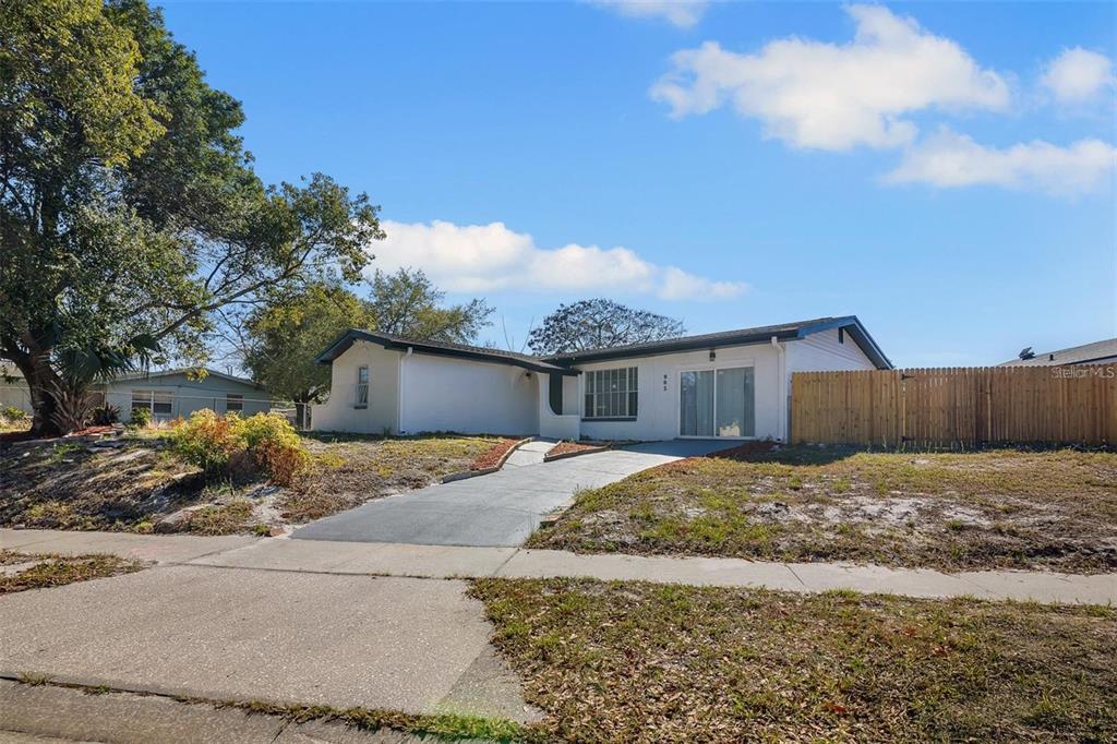 A single-story white house with a concrete driveway and a wooden fence in the yard — 905 SPRING CREEK DRIVE, OCOEE, FL