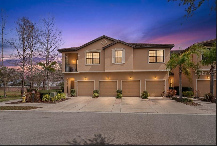 A two-story townhouse exterior features four garage doors and a second-floor balcony at dusk — 4307 VIA PIEDRA CIRCLE UNIT 6-102, SARASOTA, FL