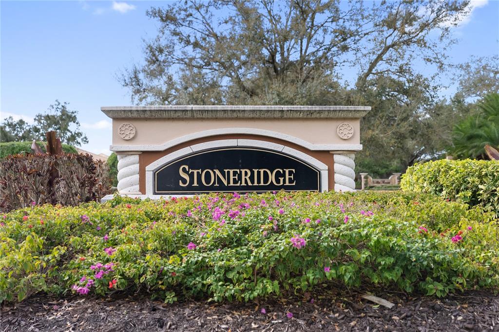 A stone neighborhood entrance sign with the name Stoneridge sits behind a flowering hedge — 4307 VIA PIEDRA CIRCLE UNIT 6-102, SARASOTA, FL
