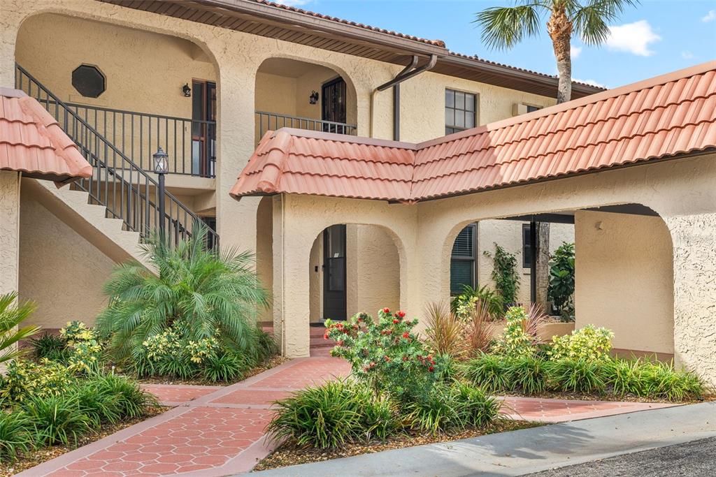 A two-story stucco building features a tiled roof, arched walkways, and a landscaped courtyard — 371 NW 14TH PLACE, CRYSTAL RIVER, FL