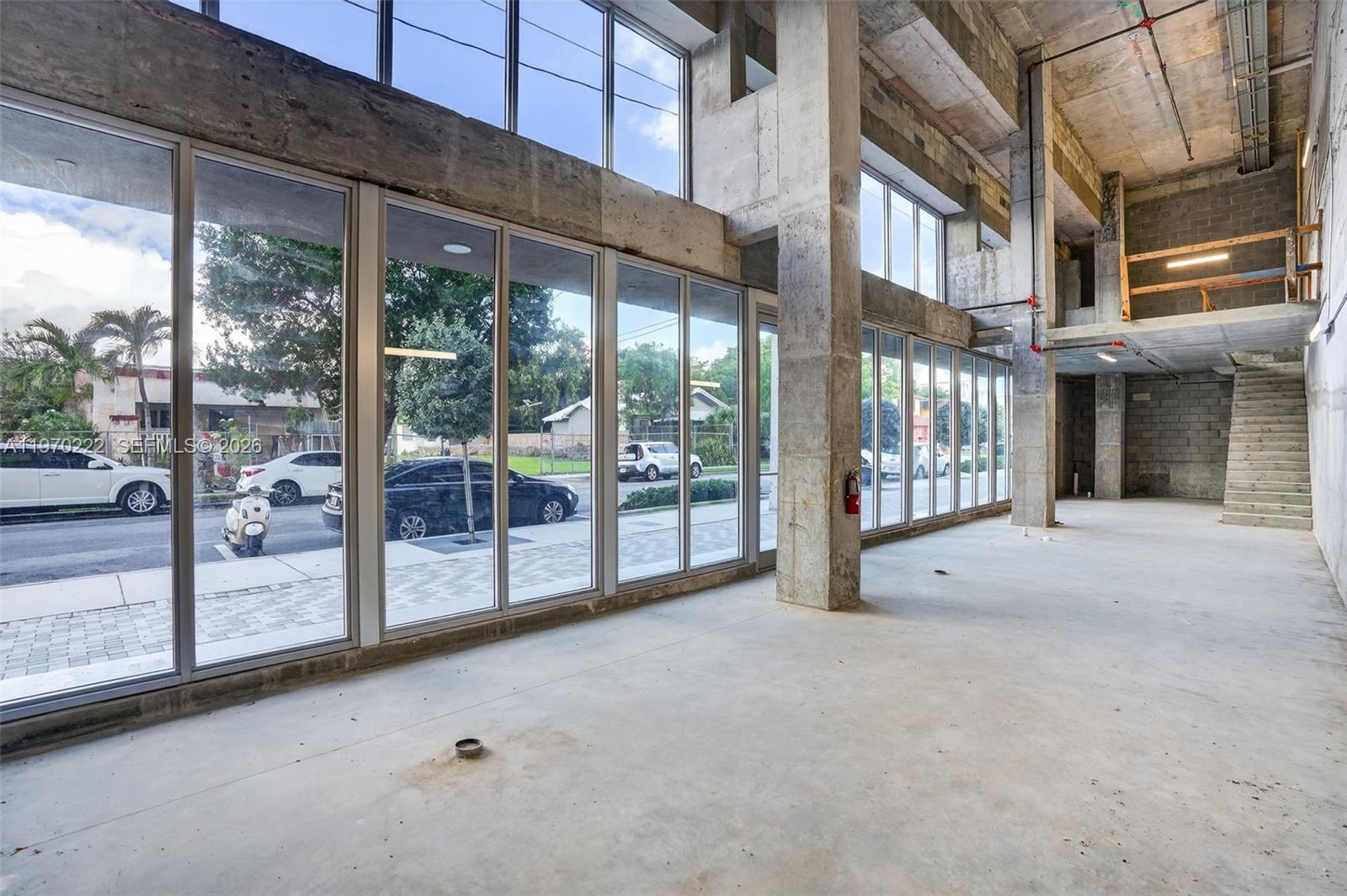 An unfinished commercial space features concrete floors, exposed ceilings, and floor-to-ceiling glass windows — 1110 NW 1 ST, Miami FL 33128, MIAMI, FL