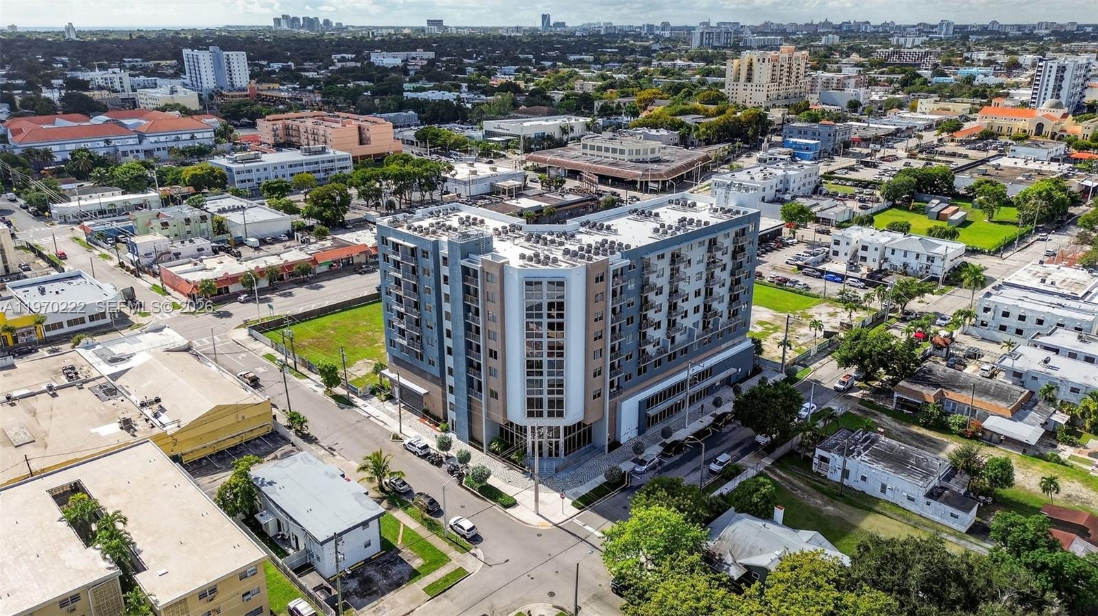 An aerial view shows a modern multi-story apartment building surrounded by urban streets and houses — 1110 NW 1 ST, Miami FL 33128, MIAMI, FL