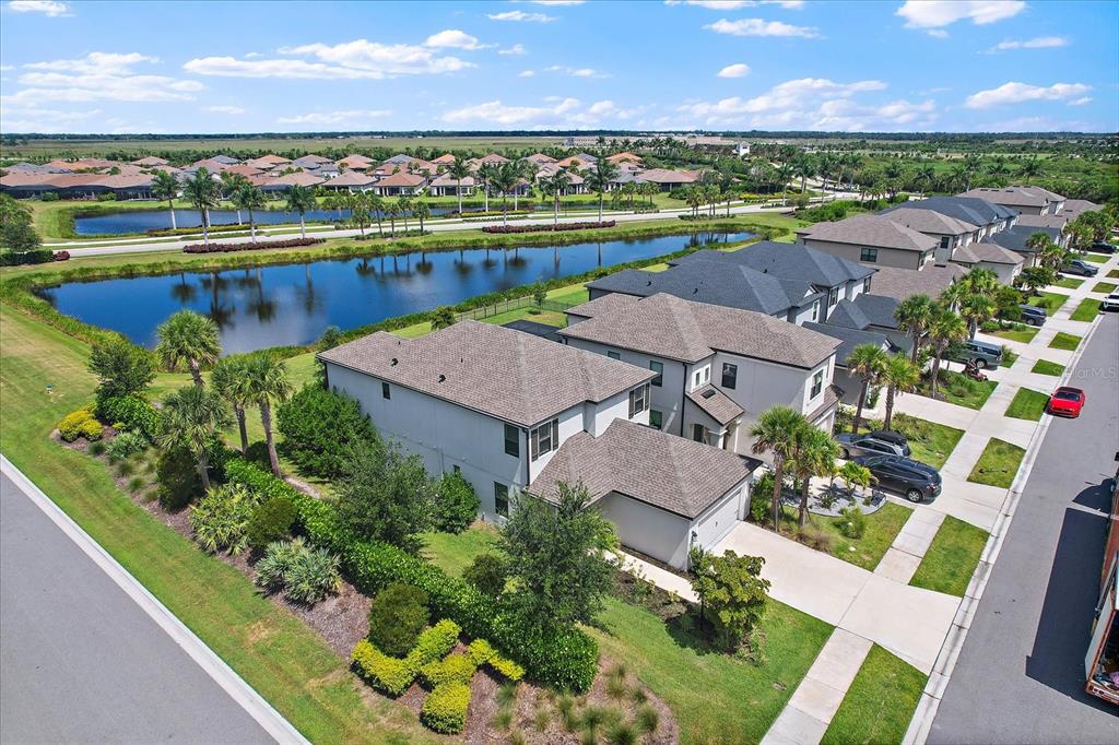An aerial view shows a two-story house with a brown roof near a large pond — 10141 MILKY WAY CIRCLE, SARASOTA, FL
