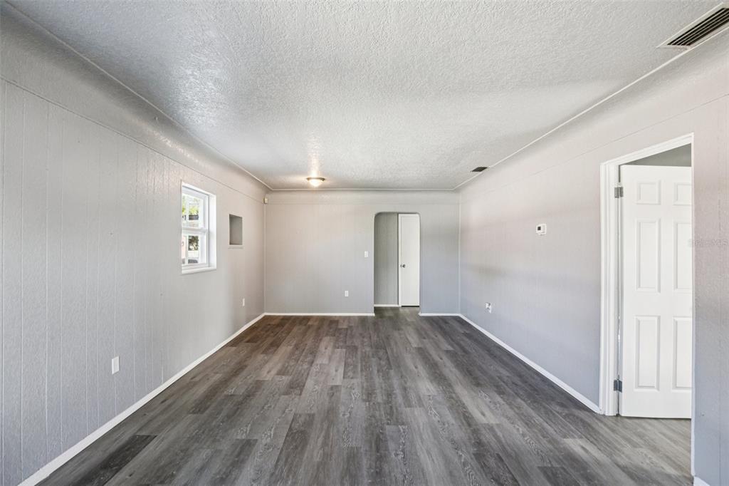 An empty room features gray wood-look flooring, light gray walls, and a white interior door — 1911 22ND AVENUE S, ST PETERSBURG, FL