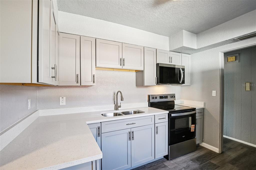 A kitchen features light gray cabinets, white countertops, stainless steel appliances, and dark wood flooring — 1911 22ND AVENUE S, ST PETERSBURG, FL