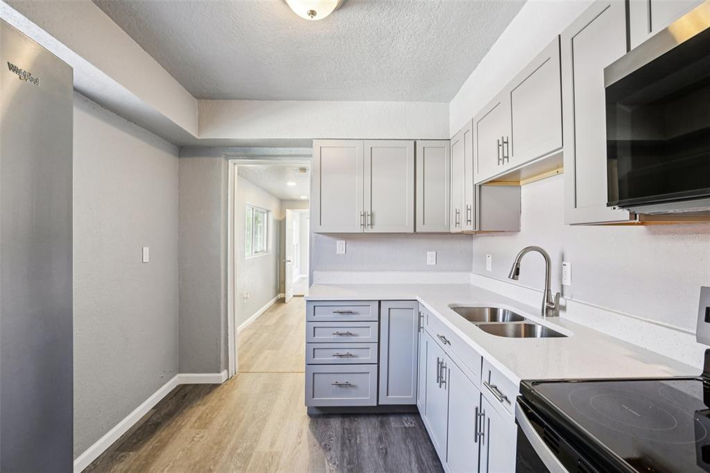 A kitchen with gray cabinets, white countertops, stainless steel appliances, and wood-look flooring — 1911 22ND AVENUE S, ST PETERSBURG, FL