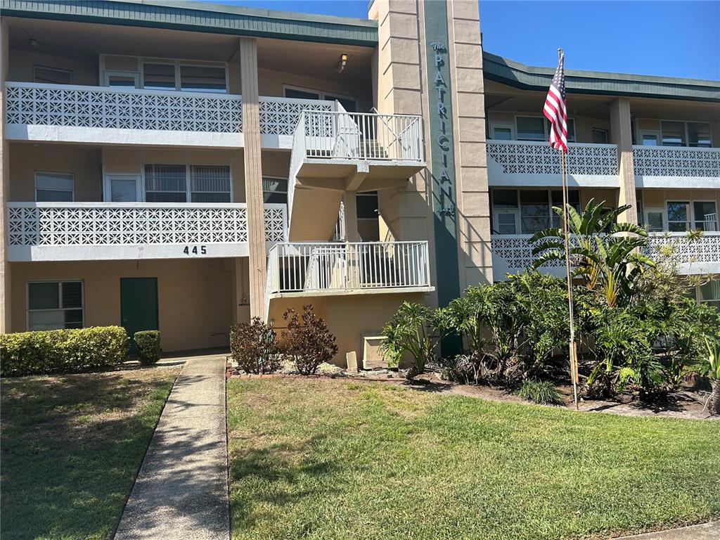 The exterior of a multi-story apartment building features a concrete staircase and decorative railings — 445 32ND AVENUE N UNIT E109, ST PETERSBURG, FL