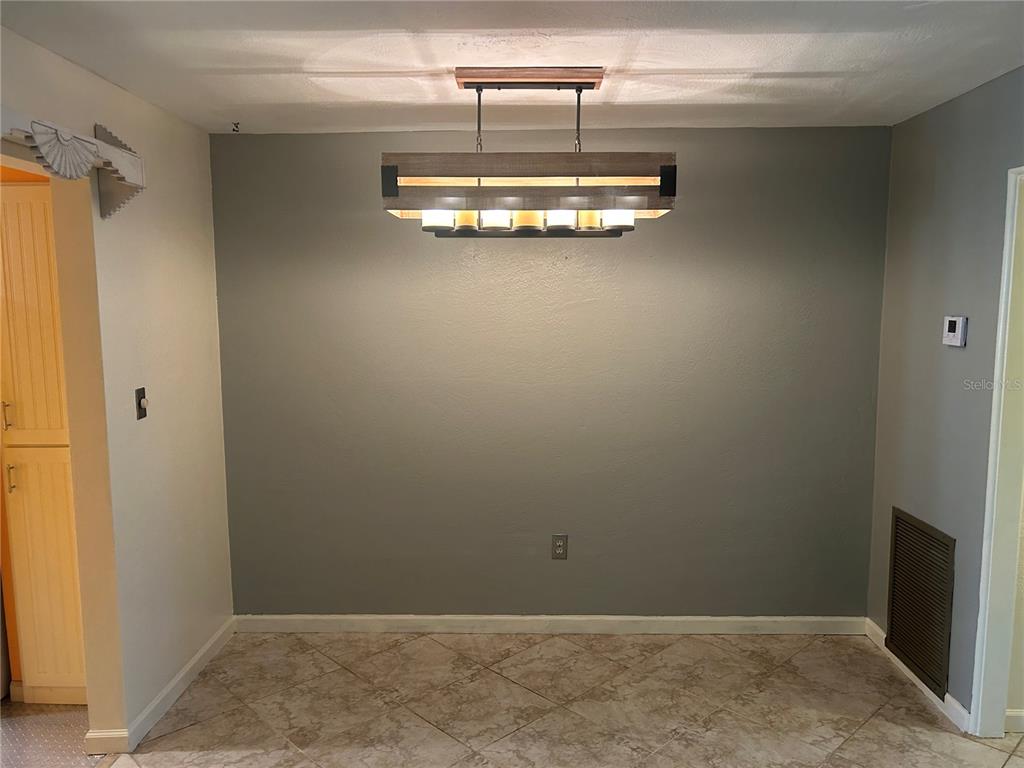 A dining area features a rectangular wood and metal chandelier centered above a gray wall — 445 32ND AVENUE N UNIT E109, ST PETERSBURG, FL