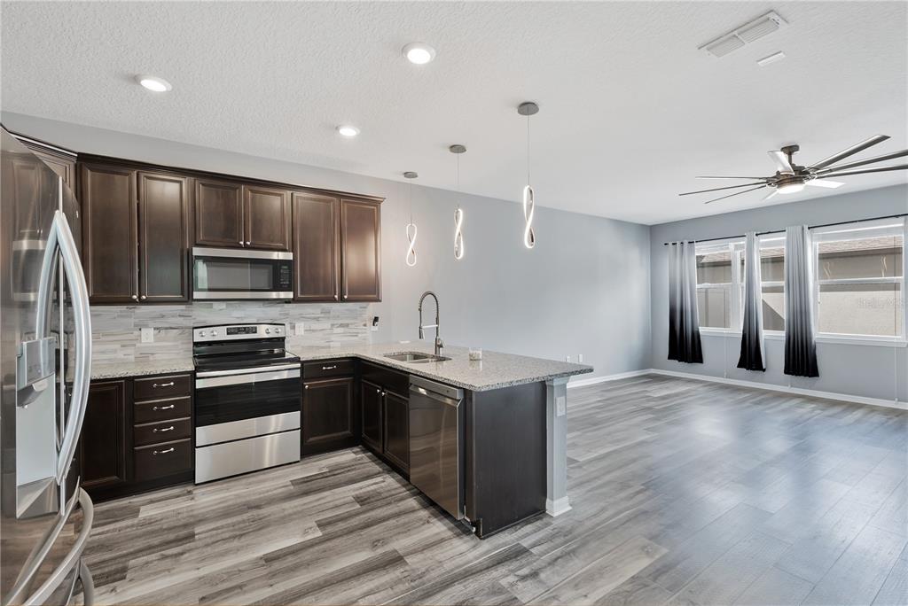 A kitchen with dark wood cabinets, stainless steel appliances, and an island with a sink — 5041 CASPIAN STREET, ST CLOUD, FL