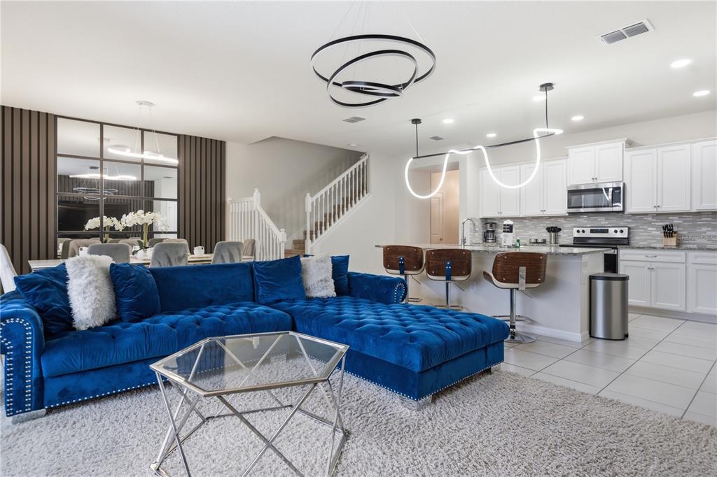 A bright open-concept living room and kitchen featuring a blue tufted sectional sofa — 3954 LANA AVENUE, DAVENPORT, FL