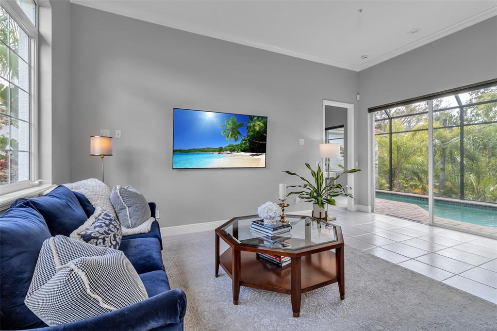 A living room features a large sectional sofa, a ceiling fan, and a wall-mounted television — 1915 HARBOUR LINKS CIRCLE UNIT 6, LONGBOAT KEY, FL