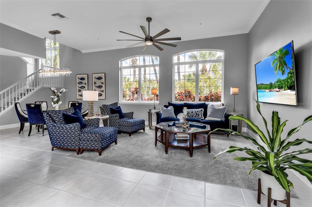 A bright living room features a large sectional sofa, a glass coffee table, and tile flooring — 1915 HARBOUR LINKS CIRCLE UNIT 6, LONGBOAT KEY, FL
