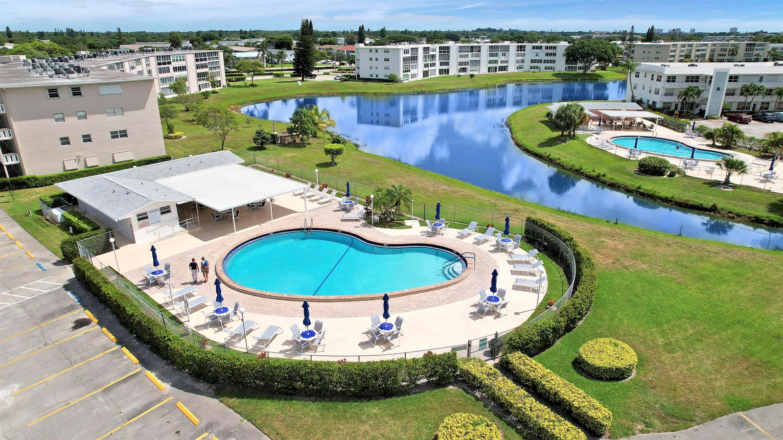 An aerial view shows a kidney-shaped swimming pool, a covered patio, and apartment buildings — 210 Wellington E, West Palm Beach FL 33417, WEST PALM BEACH, FL
