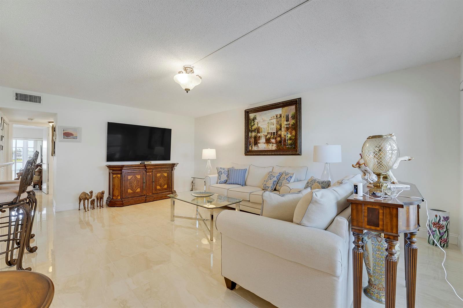 A living room features light tile flooring, a white sofa, a television, and wooden furniture — 210 Wellington E, West Palm Beach FL 33417, WEST PALM BEACH, FL