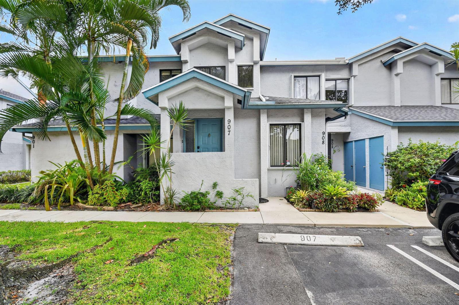 A two-story townhouse exterior features a blue front door, light gray stucco, and landscaping — 907 Harbour Pointe Way, FL 33413, FL