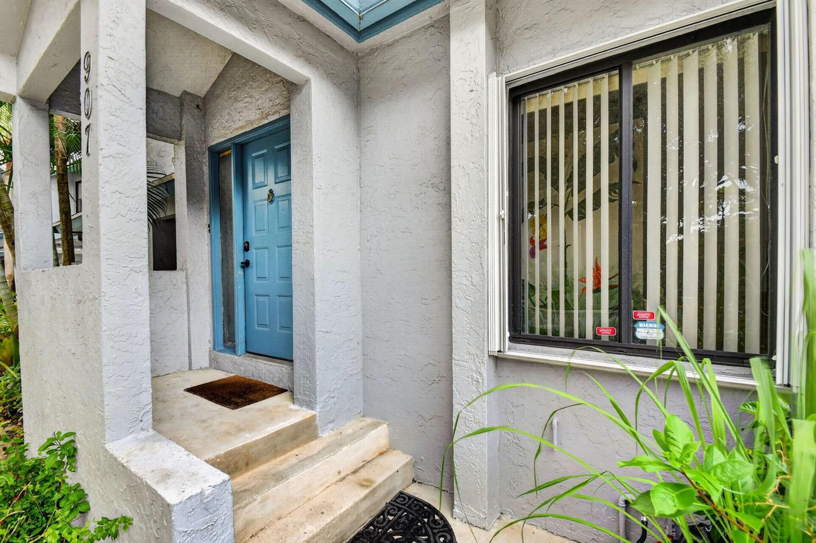 The exterior entrance features a blue door, concrete steps, and a window with vertical blinds — 907 Harbour Pointe Way, FL 33413, FL