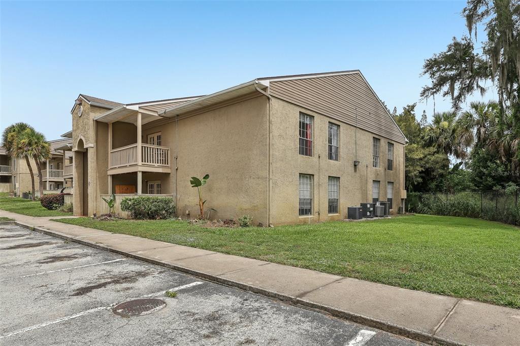 A two-story apartment building with tan stucco siding, a covered balcony, and a parking lot — 305 WYMORE ROAD UNIT 208, ALTAMONTE SPRINGS, FL