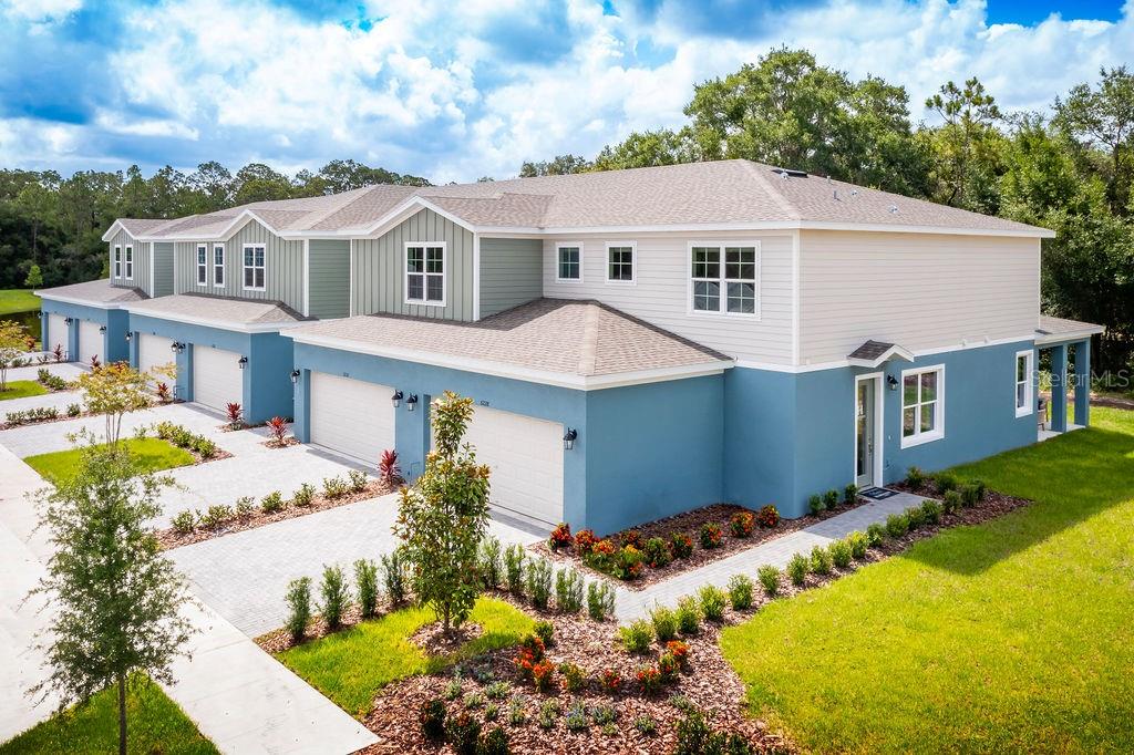 A multi-unit residential building with blue stucco, light siding, and attached garages — 5224 LUISA COURT, ST CLOUD, FL