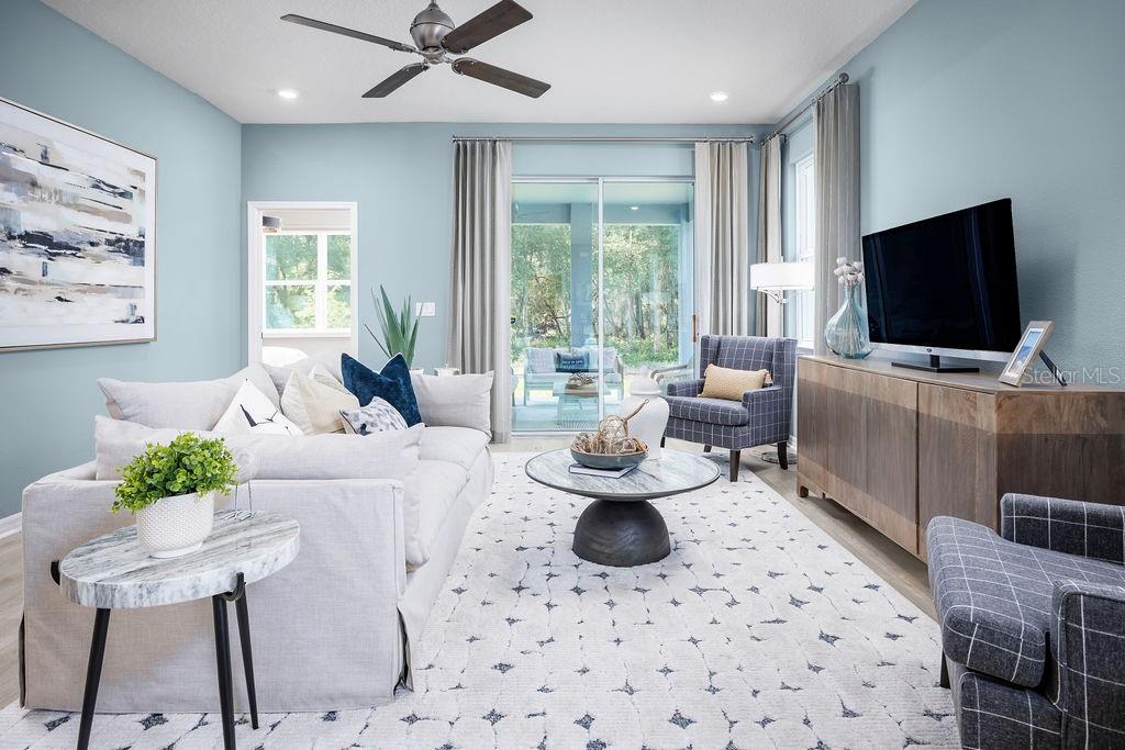 A living room features light blue walls, a gray sofa, two plaid chairs, and a television — 5224 LUISA COURT, ST CLOUD, FL