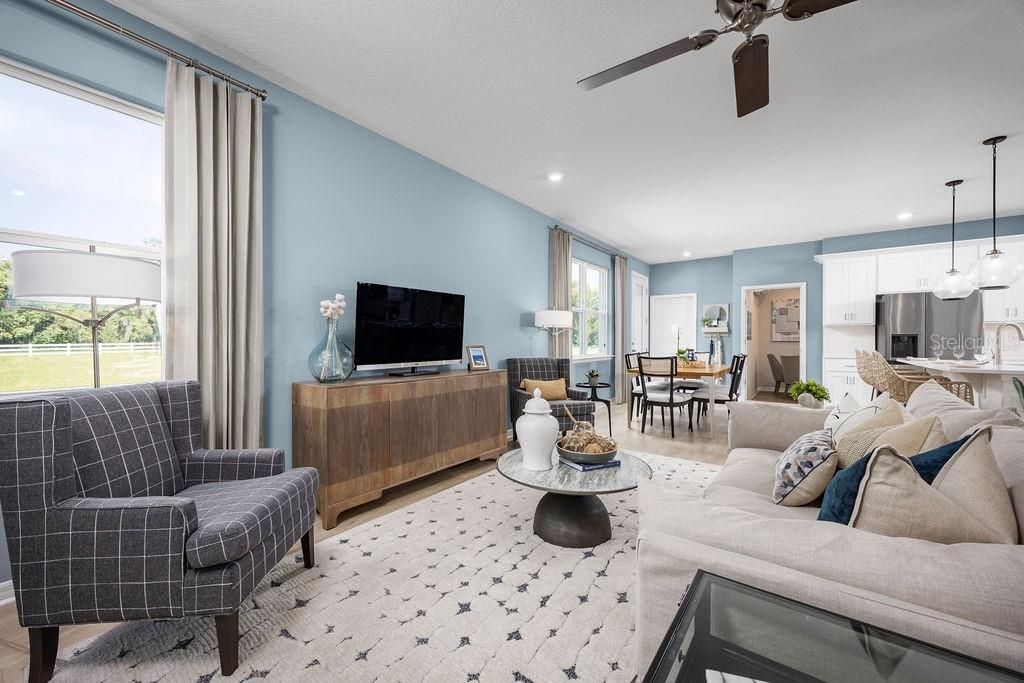 A living room with light blue walls, a plaid armchair, and an open-concept kitchen — 5224 LUISA COURT, ST CLOUD, FL