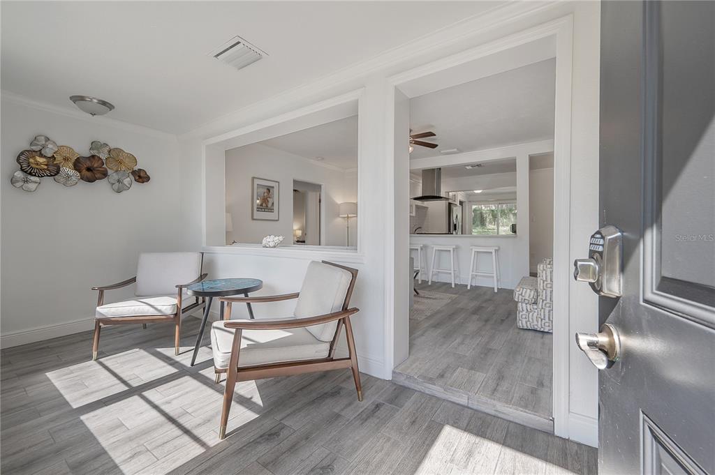 A sunlit entryway features two chairs, a small table, and a view into the kitchen — 7204 N 15TH STREET, TAMPA, FL