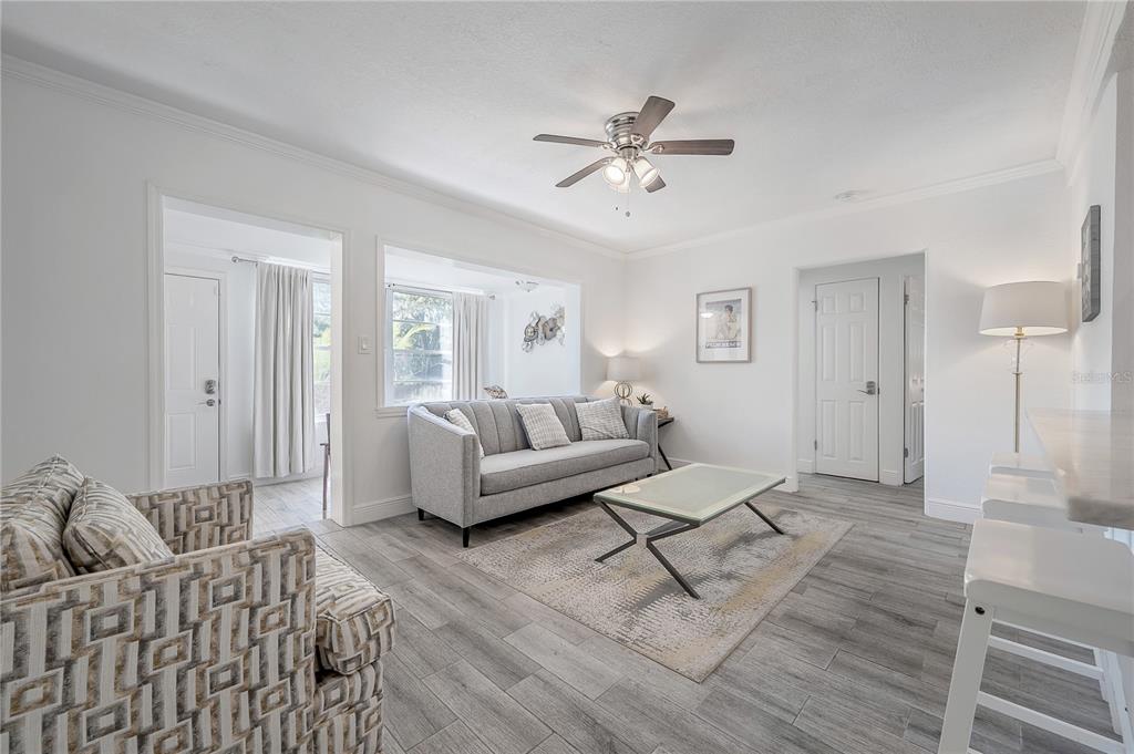A living room features gray wood-look flooring, a gray sofa, and a glass coffee table — 7204 N 15TH STREET, TAMPA, FL
