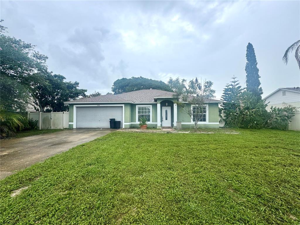 A single-story house with a green exterior, a two-car garage, and a large front lawn — 2728 CORRIGAN DRIVE, DELTONA, FL