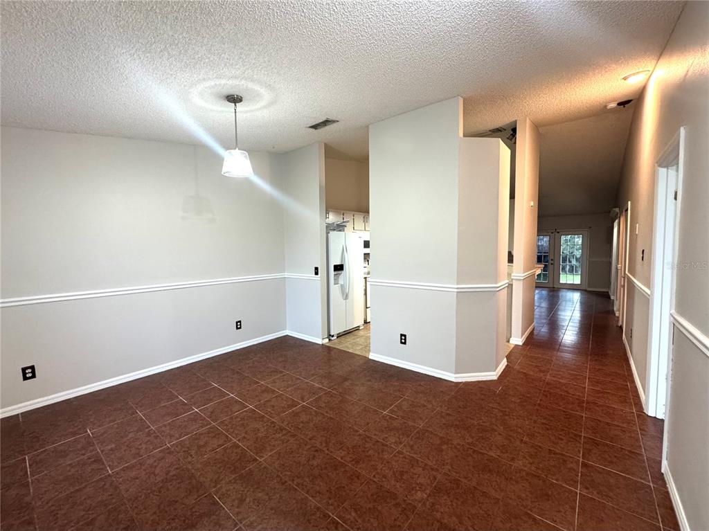 A dining area with tile floors, chair rail molding, and a view into the kitchen — 2728 CORRIGAN DRIVE, DELTONA, FL