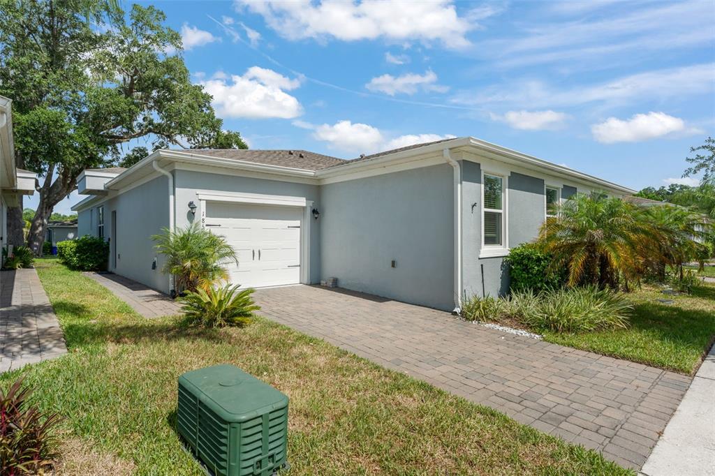 A single-story house with a white garage door, gray stucco exterior, and a paver driveway — 1858 SHUMARD AVENUE, ST CLOUD, FL