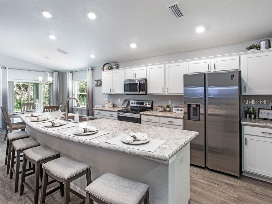 A kitchen features white cabinets, stainless steel appliances, a large island, and barstool seating — 1821 NOBLE DRIVE, DAVENPORT, FL