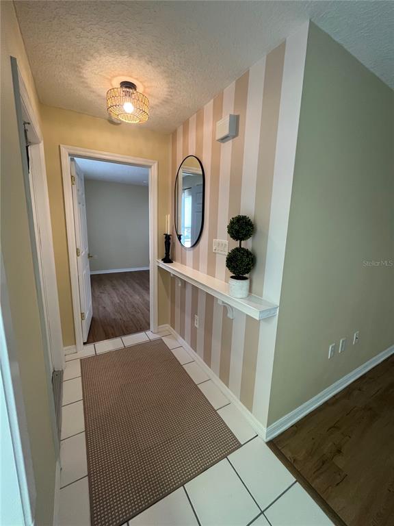 A hallway features striped wallpaper, a floating shelf, a mirror, and a light fixture — 1111 APPLE TERRACE, LEESBURG, FL