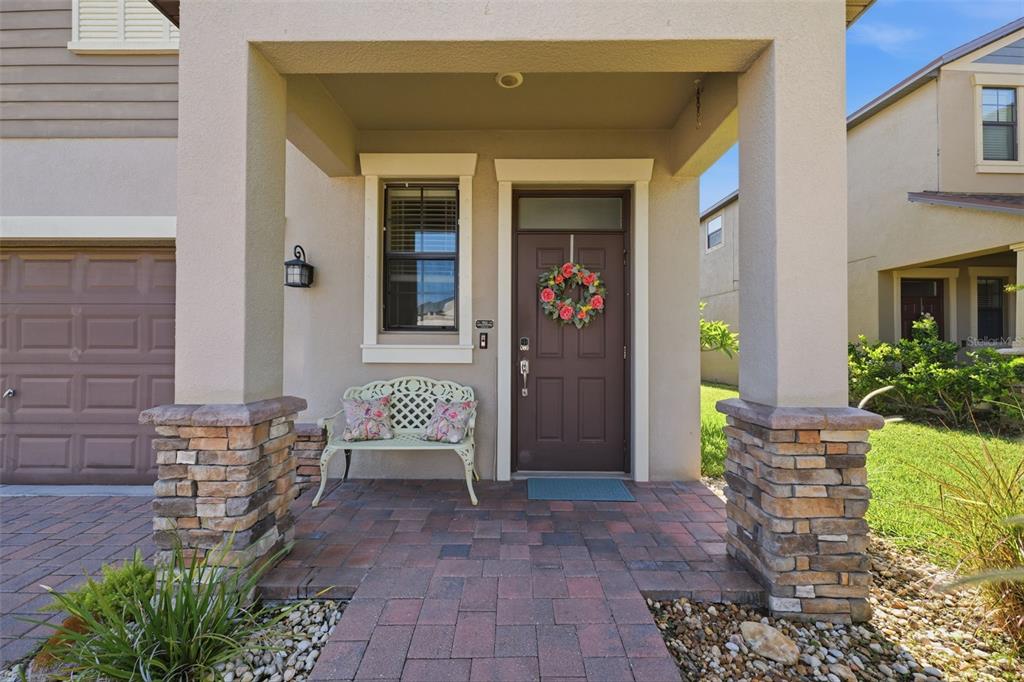 A single-story house with a brown garage, stone accents, and a paved driveway at sunset — 11767 LAKE BOULEVARD, NEW PORT RICHEY, FL